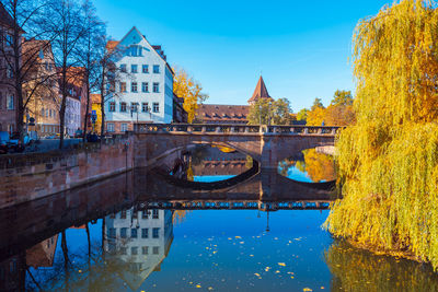 Arch bridge over river by buildings against sky