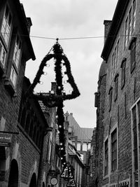 Low angle view of christmas decorations hanging amidst buildings against sky