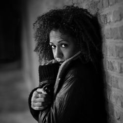 Portrait of mid adult woman in jacket standing against wall