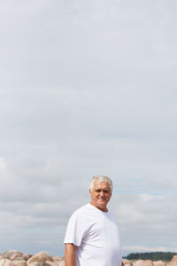 Portrait of mature man standing against sky