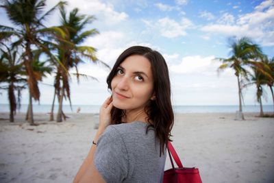 Portrait of beautiful woman at beach against sky