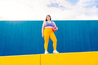 Full length of young woman standing on wall