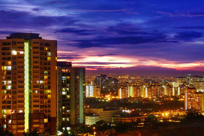 Illuminated cityscape against sky at sunset