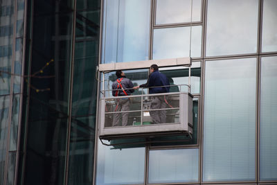 Rear view of workers standing in container on modern building