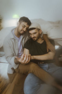 Gay couple spending leisure time sitting at home