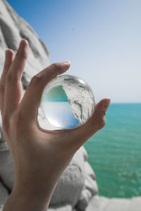 Cropped hand holding crystal ball with reflection