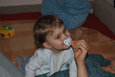 Midsection of mother putting pacifier in son mouth at home