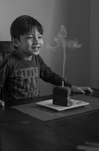 Happy boy looking at cake on table