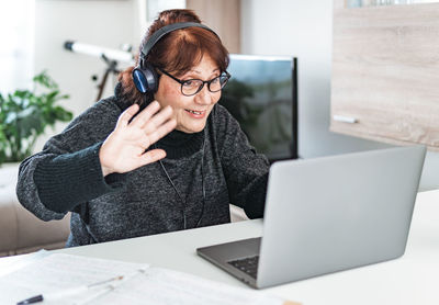 Midsection of woman using mobile phone while sitting on table