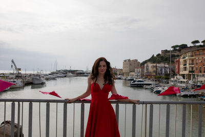 Portrait of woman standing by water against sky