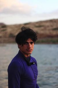 Portrait of young man standing against lake