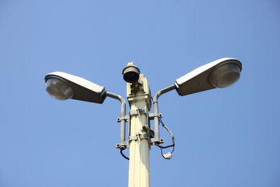 Low angle view of telephone pole against clear blue sky