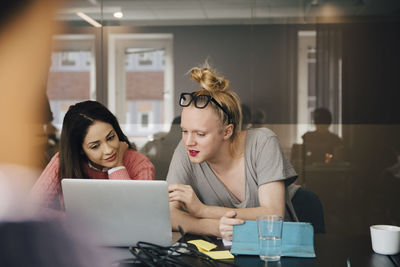 Businesswoman discussing with transgender colleague over laptop in board room during meeting