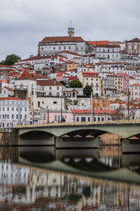 Arch bridge over river against buildings in city