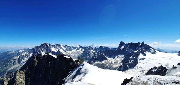 Scenic view of snowcapped mountains against blue sky