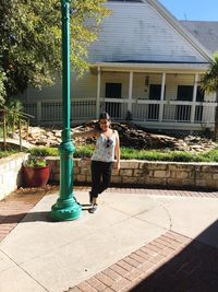 Full length of young woman standing by street light on street