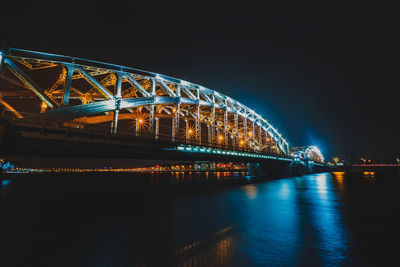 Illuminated bridge over river at night