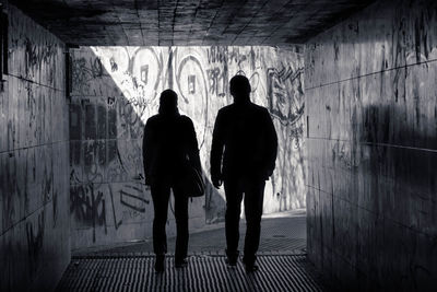 Rear view of silhouette people walking in underground walkway