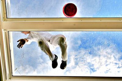 Low angle view of man on window against sky