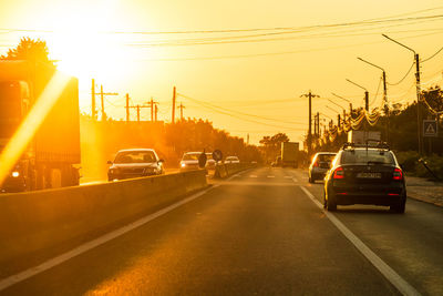 Cars on road against sky during sunset in city