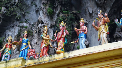 Low angle view of statues on temple roof against rock formations