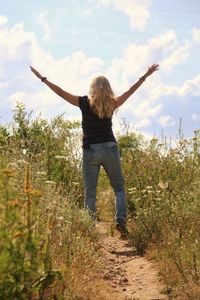 Rear view of woman standing on field against sky