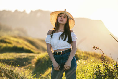 Portrait of beautiful young woman standing on field