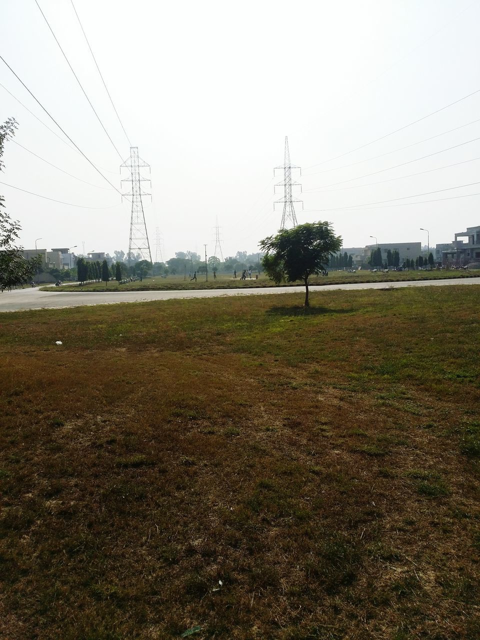 field, clear sky, landscape, grass, rural scene, electricity pylon, building exterior, power line, sky, copy space, grassy, nature, built structure, tree, agriculture, tranquil scene, tranquility, day, architecture, outdoors