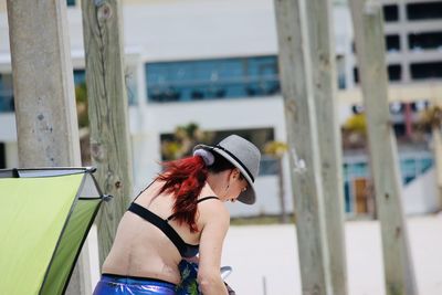 Side view of young woman standing against built structure