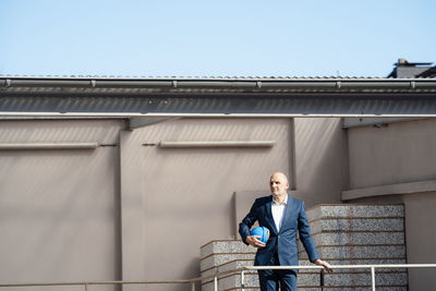 Businessman holding hardhat standing in construction site