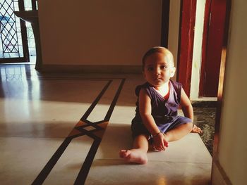 Portrait of cute boy sitting on floor at home