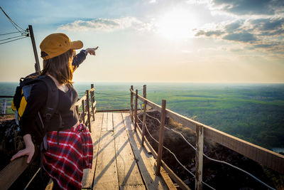Rear view of woman standing by railing against sea