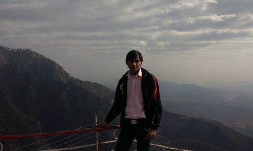 Young man looking at mountains against sky