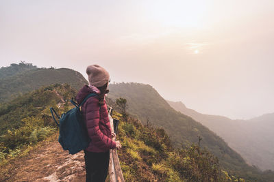 Rear view of man standing on mountain against sky