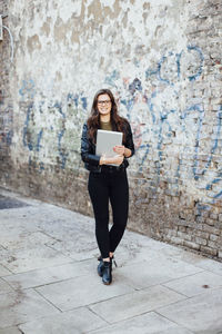 Portrait of young man standing against wall