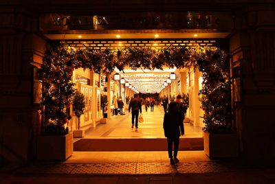 People walking on illuminated street at night