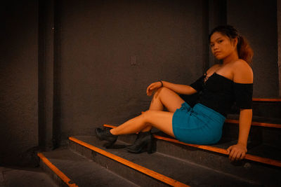 Young woman looking away while sitting on floor