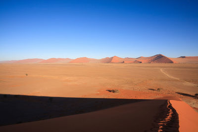 Scenic view of desert against clear blue sky