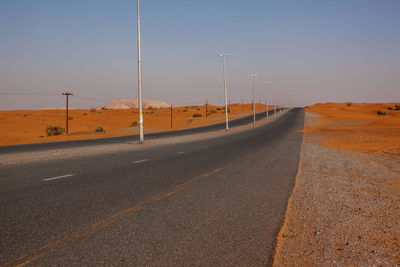 Winding black asphalt road through sand dunes, united arab emirates