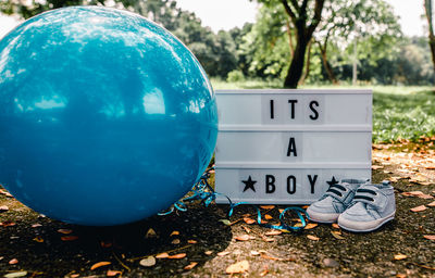 Close-up of booties by sign with text and balloon on land