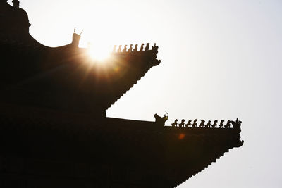 Low angle view of silhouette people on building against sky during sunset