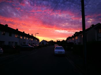 Cars on road against cloudy sky at sunset