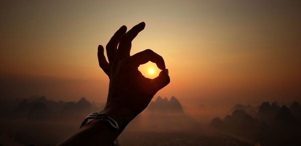 Silhouette person against orange sky during sunset