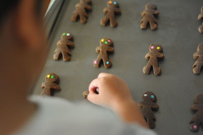 Cropped image of boy arranging gingerbread cookies on tray