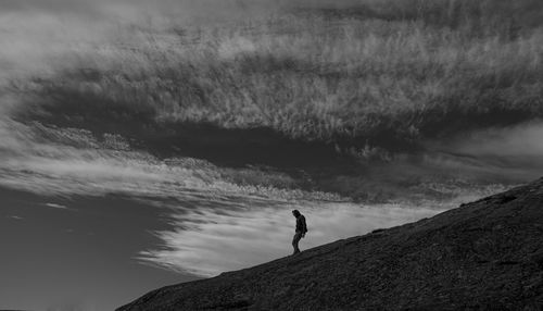 Man standing on rock against sky