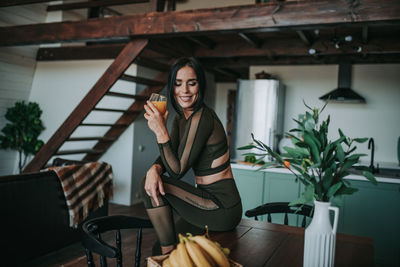 Full length of young woman sitting on table