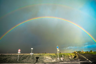 Rainbow over landscape against cloudy sky