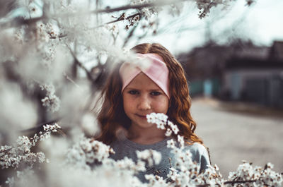 Portrait of woman with pink flowers against blurred background