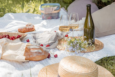 Aesthetic picnic outdoors with wine glasses bread berries and flowers. rustic picnic