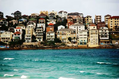 Buildings by sea against sky